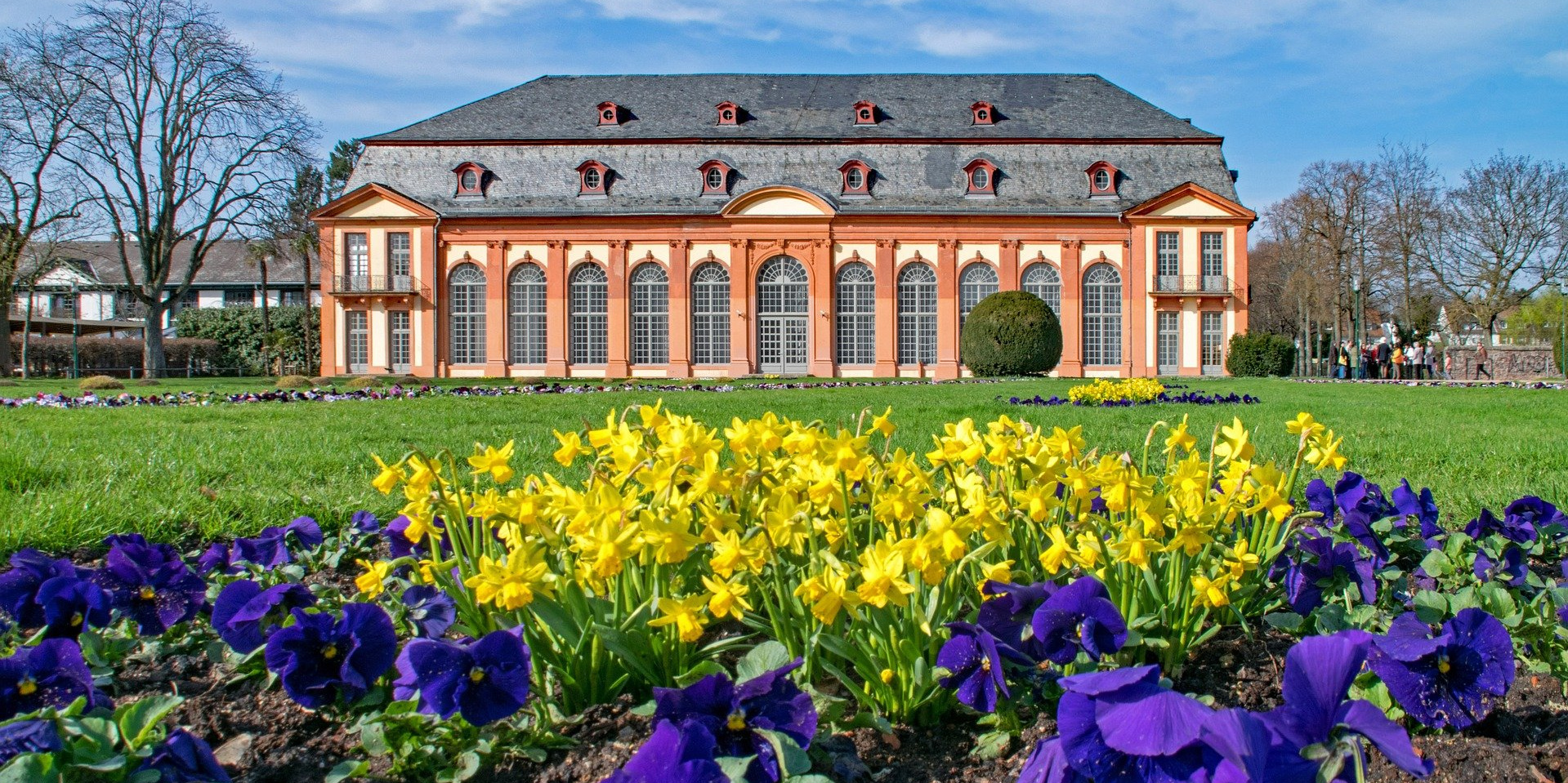 Bild von der Orangerie in Darmstadt und im Vordergrund blühen schöne Blumen