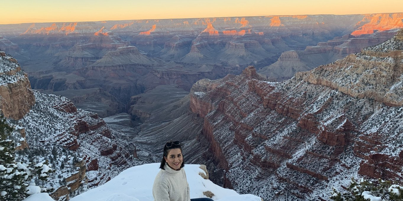 Eine Studentin der h-da im Auslandssemester sitzt auf einem mit Schneebedeckten Berg inmitten eines großen Gebirges